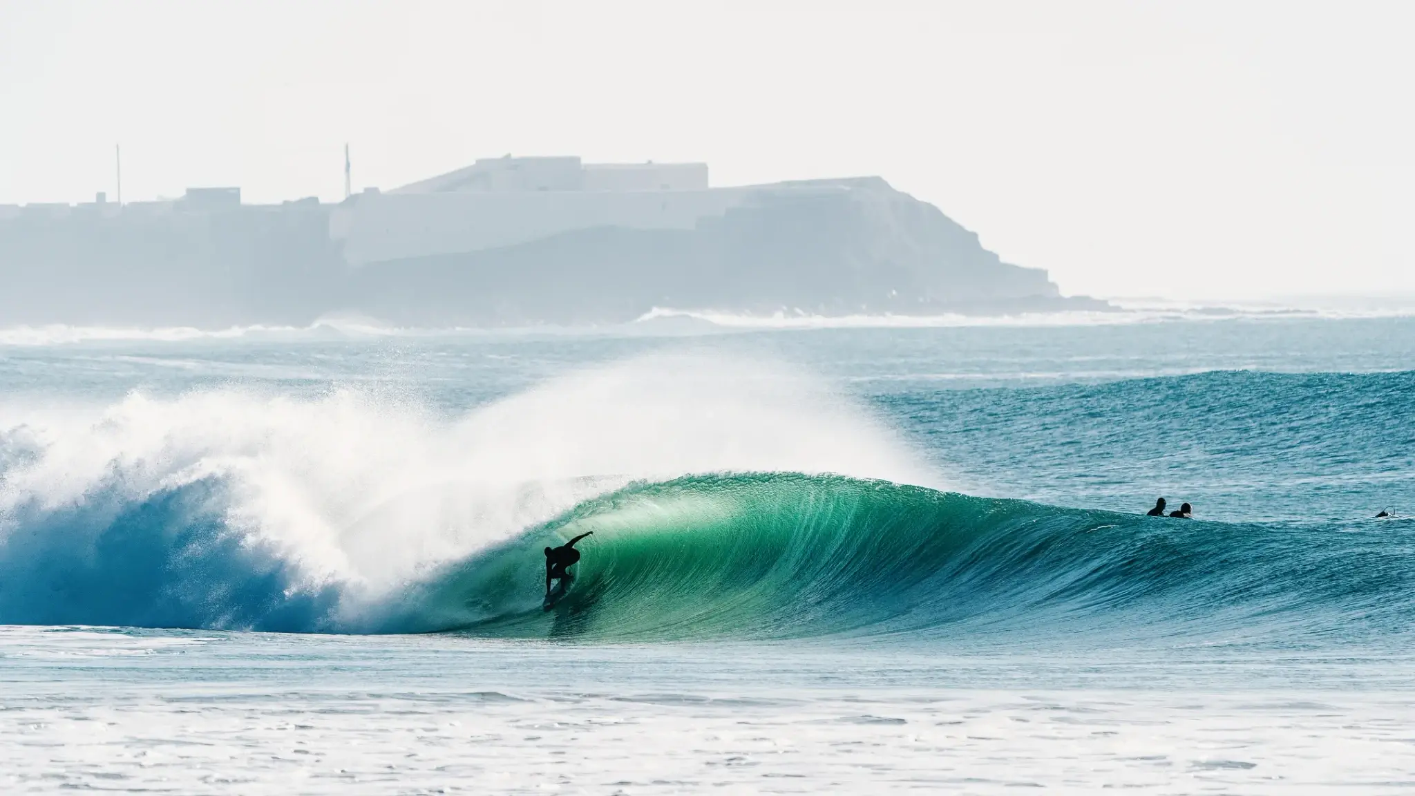A surfer riding a turquoise barrel at Supertubos, Peniche